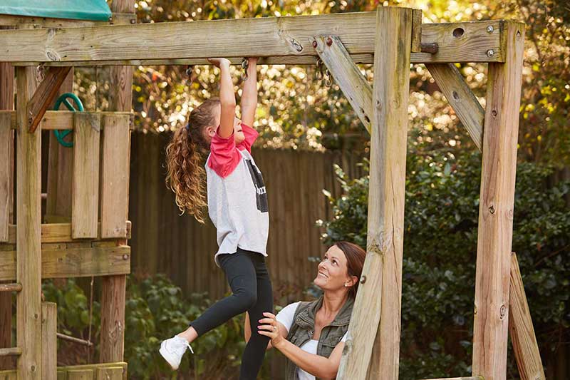mom watching daughter on monkey bars